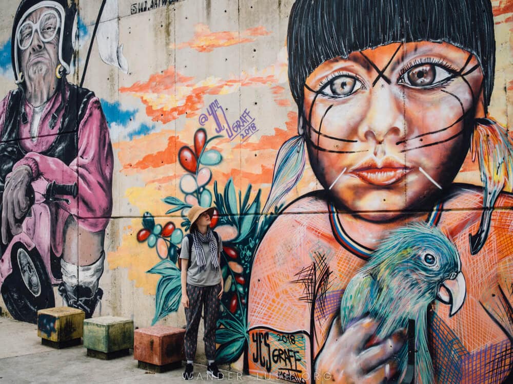 Una mujer se para frente a un mural callejero en Medellín, Colombia.